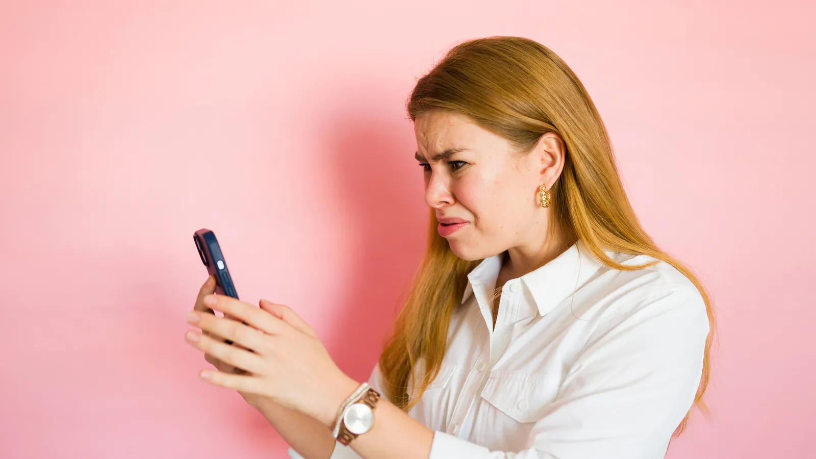 A woman frowning at her phone, waiting for a reply
