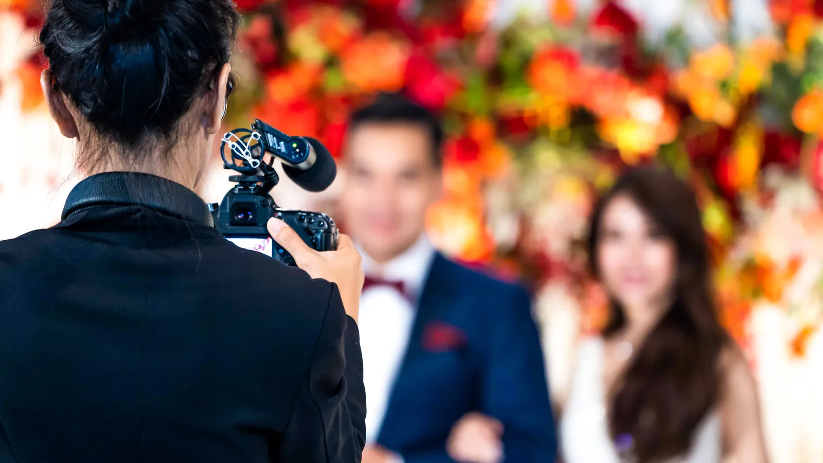 A videographer filming a bride and groom at their wedding