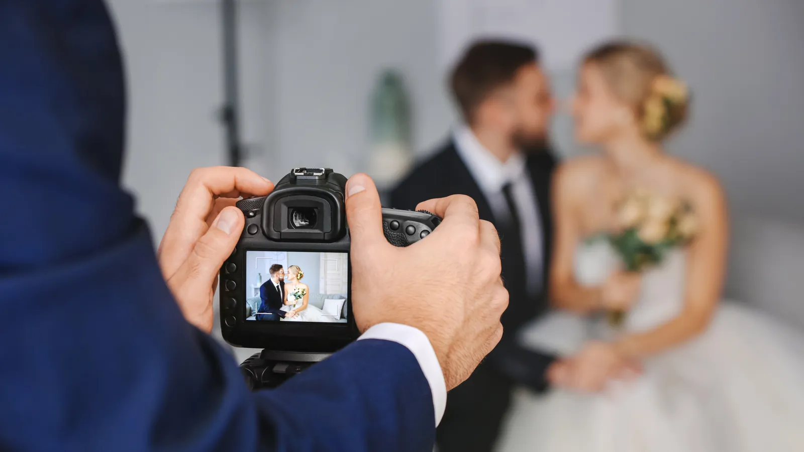A photographer framing a bride and groom on the back screen of a camera