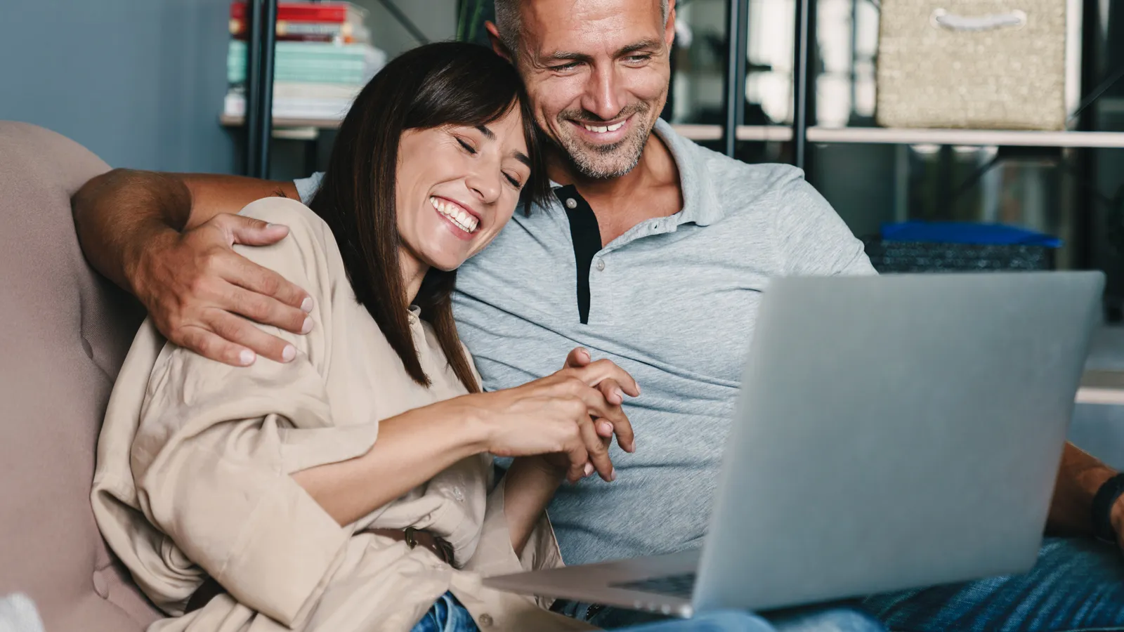 A couple on a sofa smiling at photos on a laptop