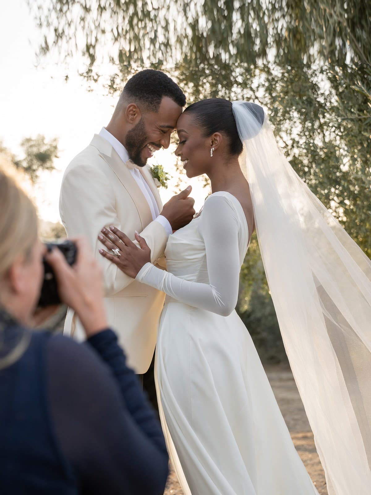 A bride and groom at the altar, foreheads together, the photographer in the foreground