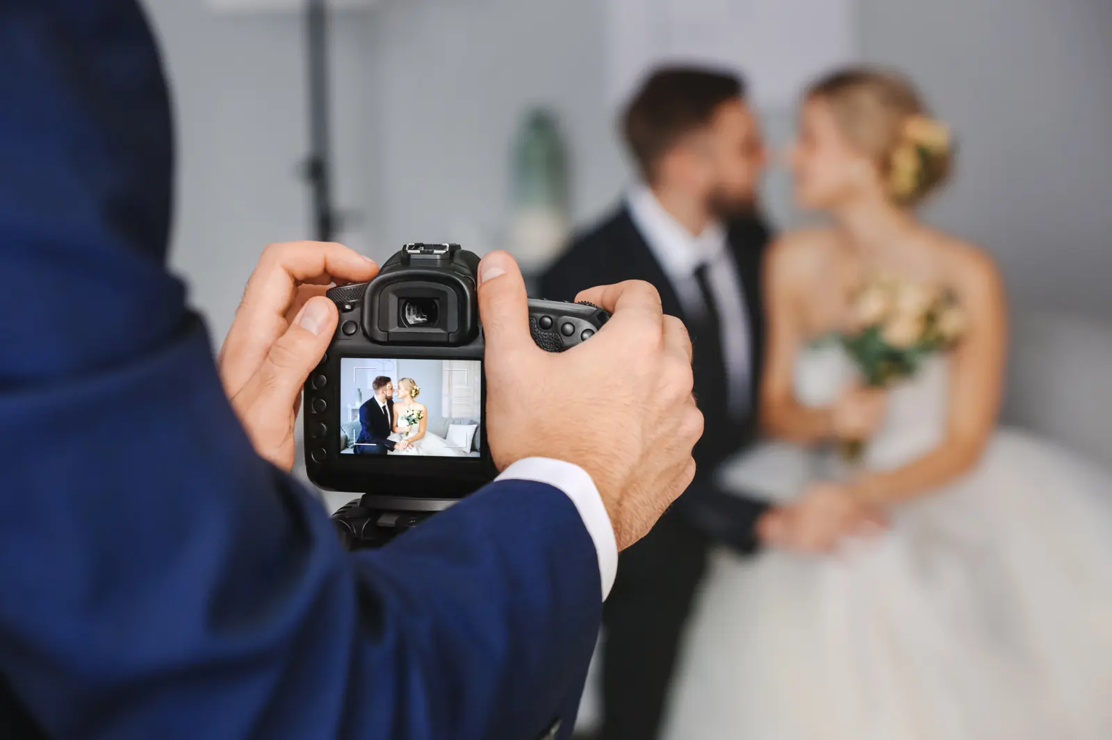 A photographer showing a wedding couple the back of the camera