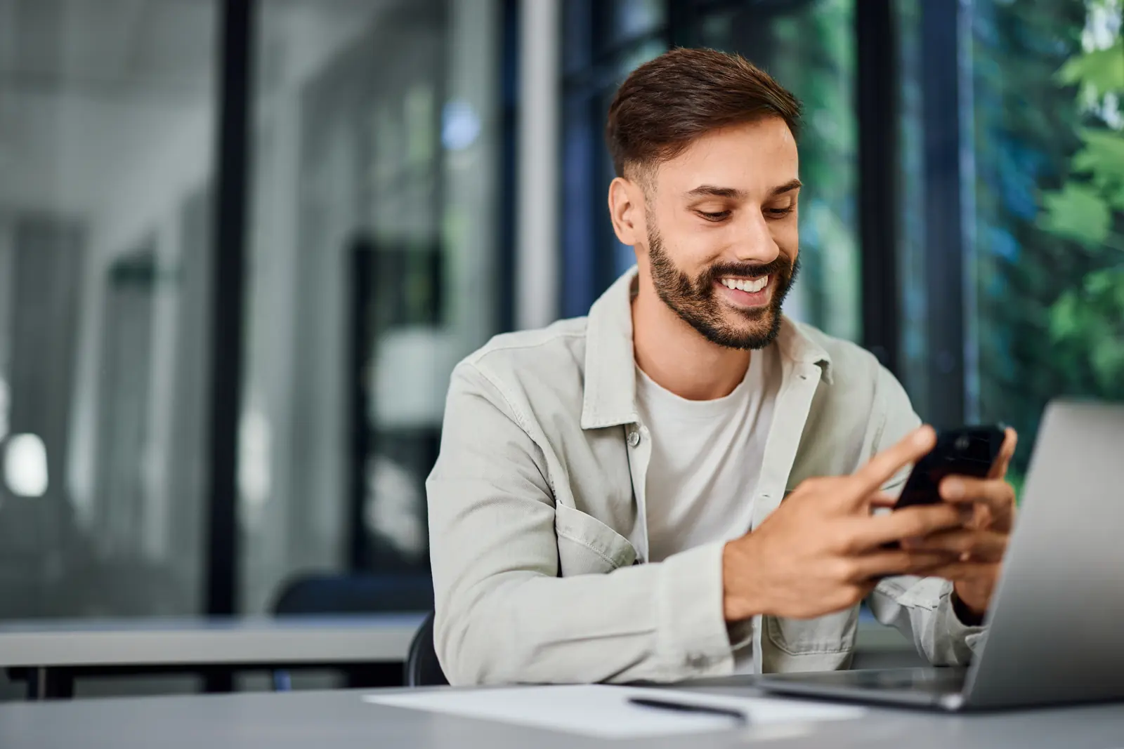 A crew member smiling at his phone at his laptop