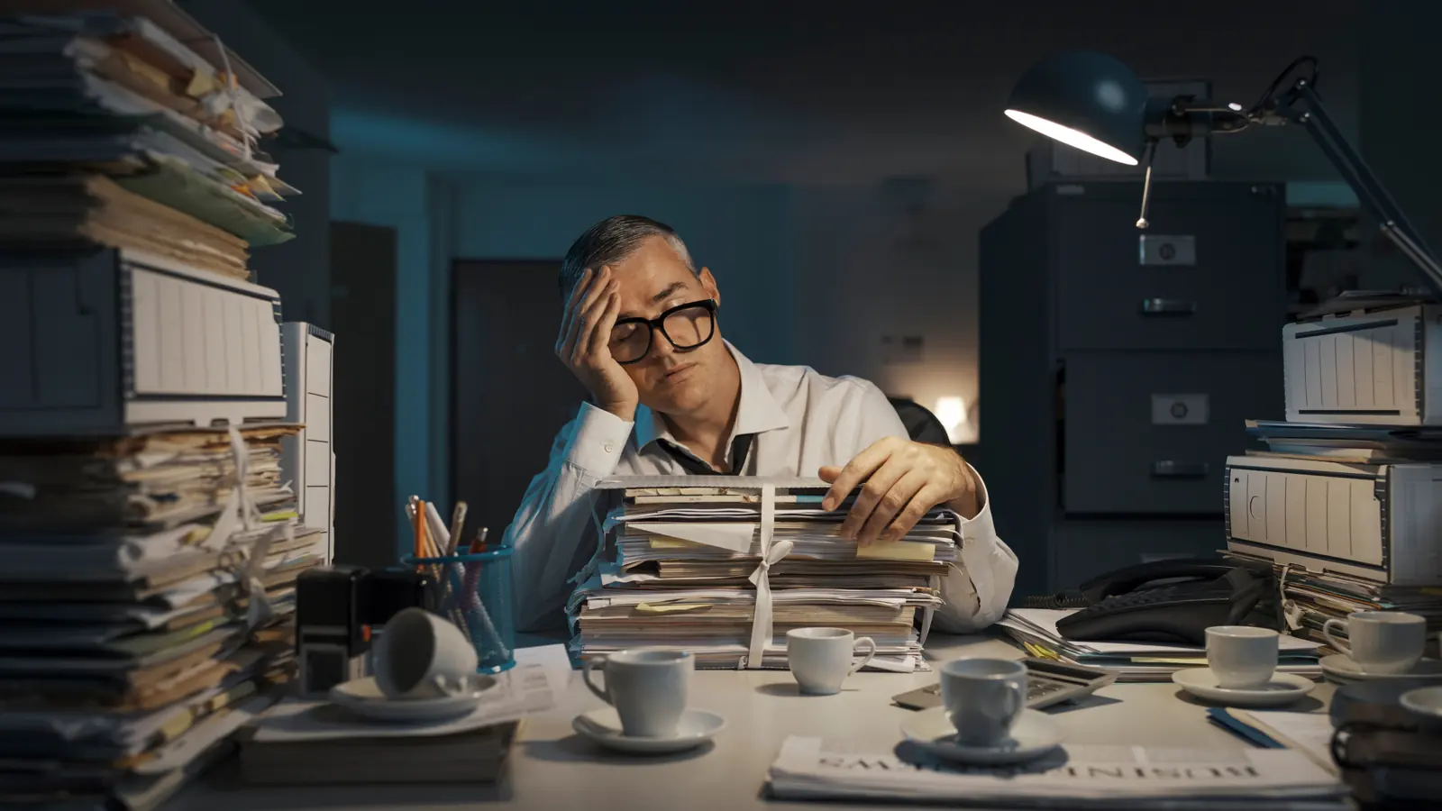 A studio owner working late, buried in paperwork
